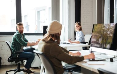 Picture of young colleagues work in office using computers. Looking aside.